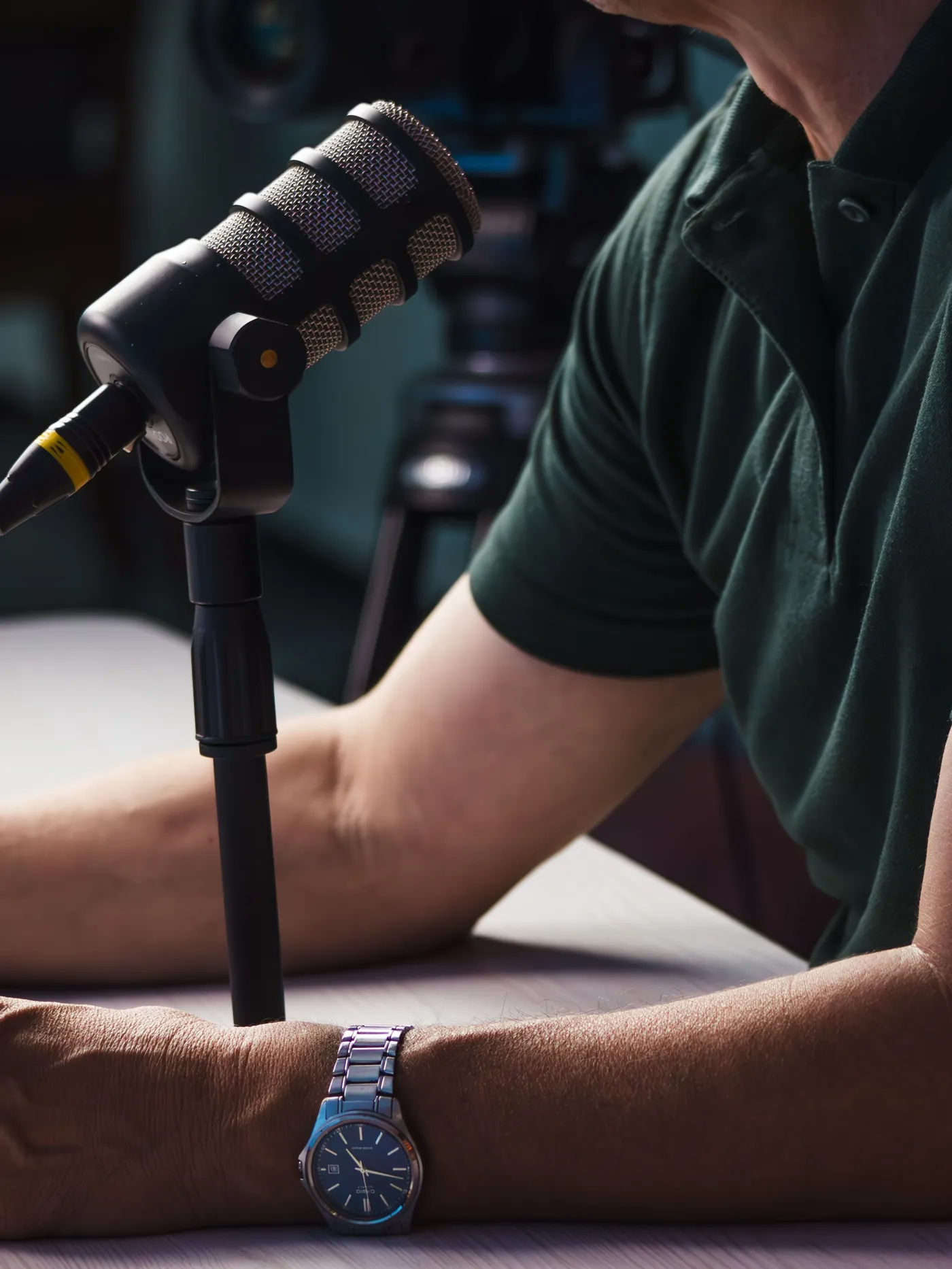 Detalle de un micrófono de podcast y un reloj de pulsera sobre una mesa durante una grabación